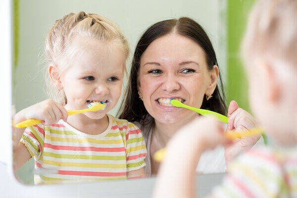 Mother-teaching-daughter-brush-teeth-Stock-Photo-03